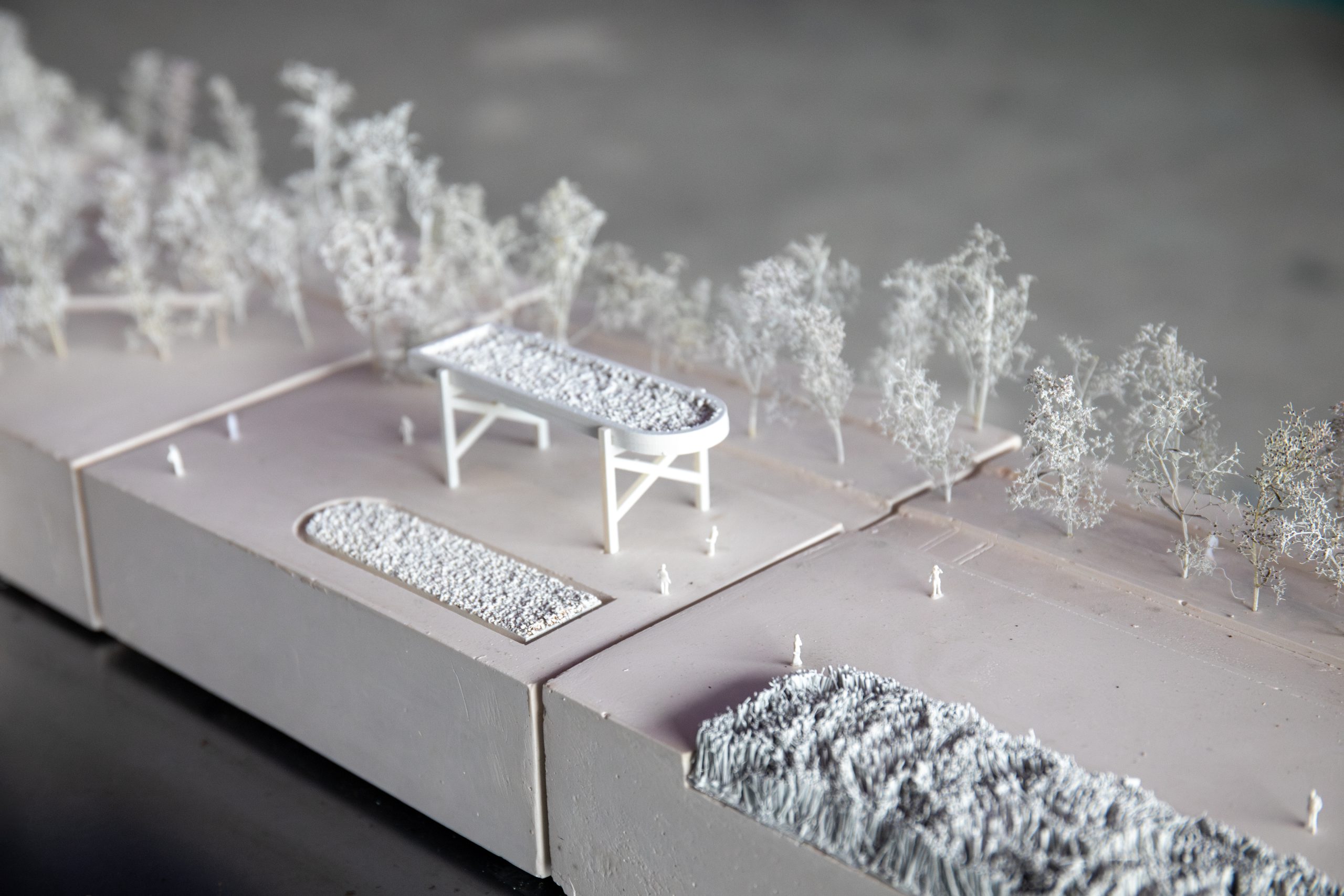 A close up photo of a white architectural model of what Ravenscraig could look like in the future, featuring model trees and people.